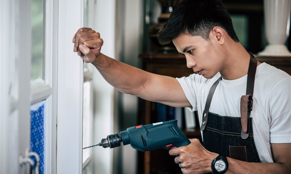 Installer drilling and fitting a window frame during installation work
