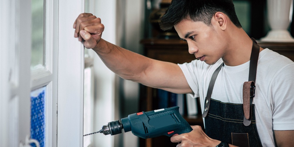 Installer drilling and fitting a window frame during installation work