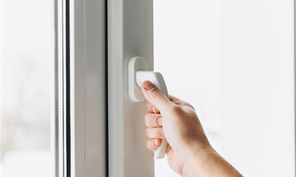 Hand operating a window handle during a hardware inspection