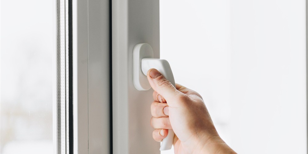 Hand operating a window handle during a hardware inspection