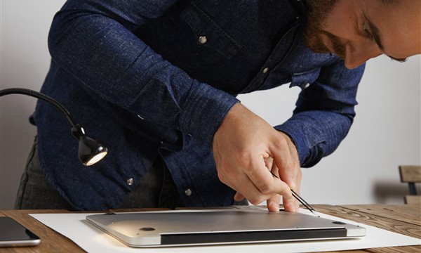 Technician inspecting the underside of a used laptop before purchase