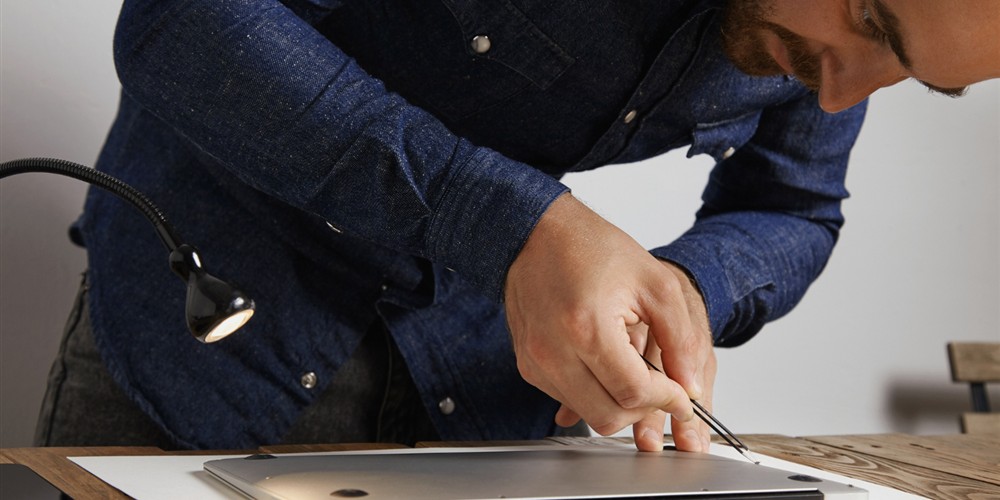 Technician inspecting the underside of a used laptop before purchase